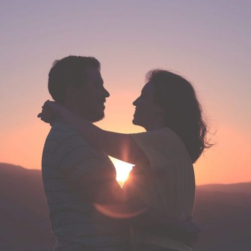a man and woman looking at each over in the sunset